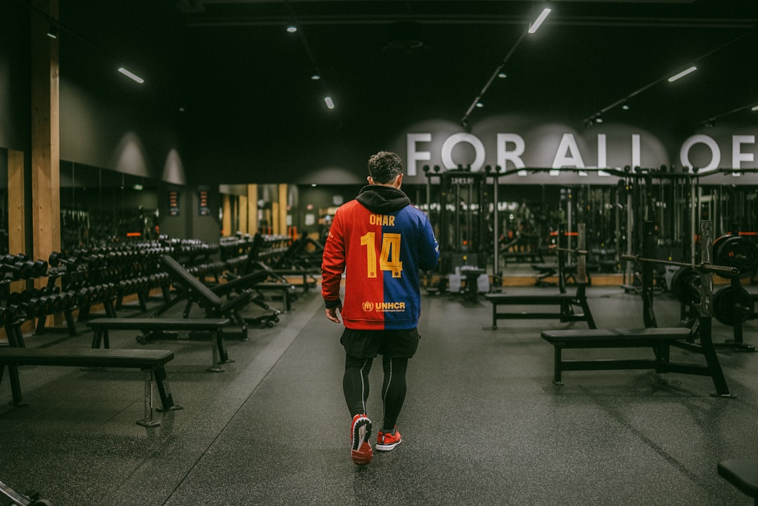 Person in a numbered jacket walks through a dark gym.